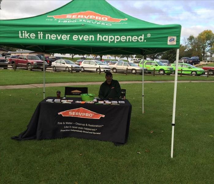 One SERVPRO representative under at a SERVPRO table on a golf course