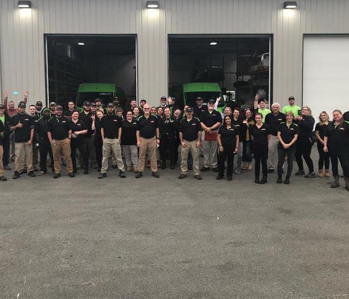large group of SERVPRO staff in front of a tan building